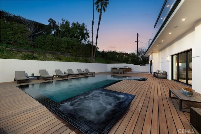 pool at dusk with a wooden deck