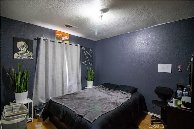 bedroom with hardwood / wood-style flooring and a textured ceiling