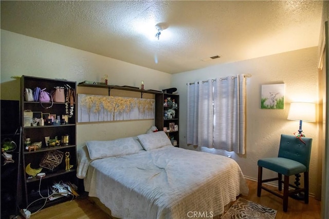 bedroom with a textured ceiling and hardwood / wood-style flooring