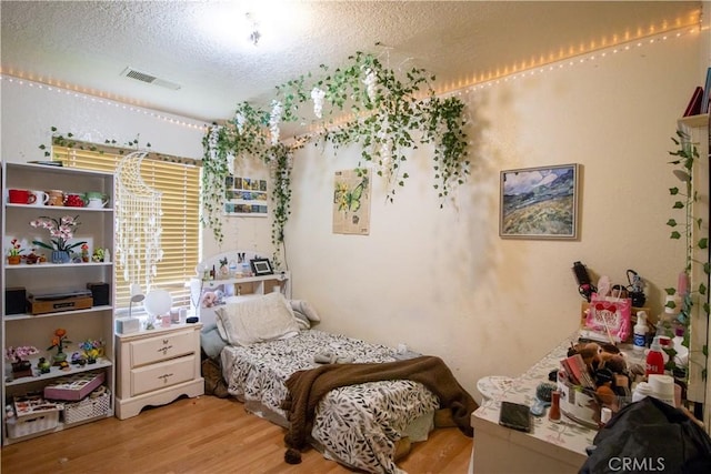 bedroom with light wood-type flooring and a textured ceiling