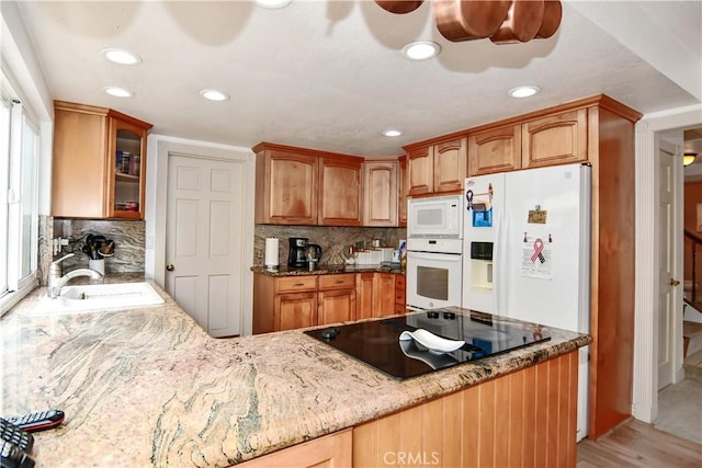 kitchen featuring light stone countertops, sink, white appliances, and decorative backsplash