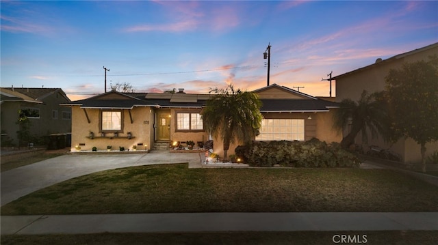 ranch-style house featuring a lawn and solar panels