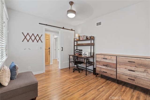 office featuring hardwood / wood-style flooring, a barn door, and ceiling fan