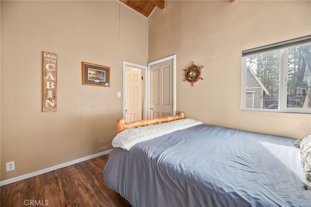 bedroom with high vaulted ceiling, baseboards, and dark wood-style flooring