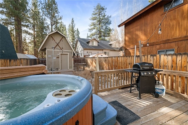 wooden deck featuring a fenced backyard, a shed, grilling area, an outdoor structure, and a hot tub