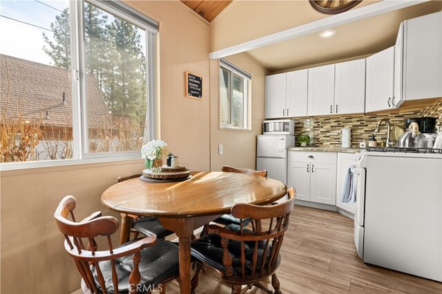 dining space featuring vaulted ceiling, a healthy amount of sunlight, and light hardwood / wood-style floors