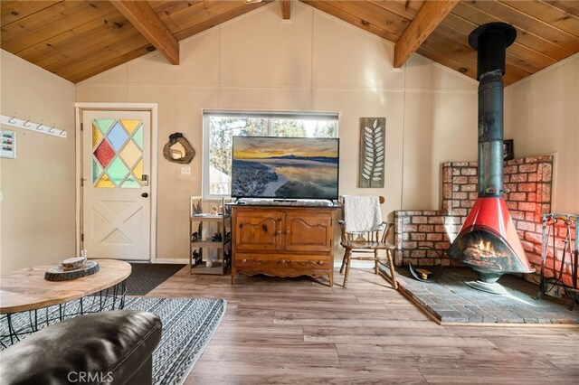 living room with lofted ceiling with beams, a wood stove, hardwood / wood-style floors, and wooden ceiling