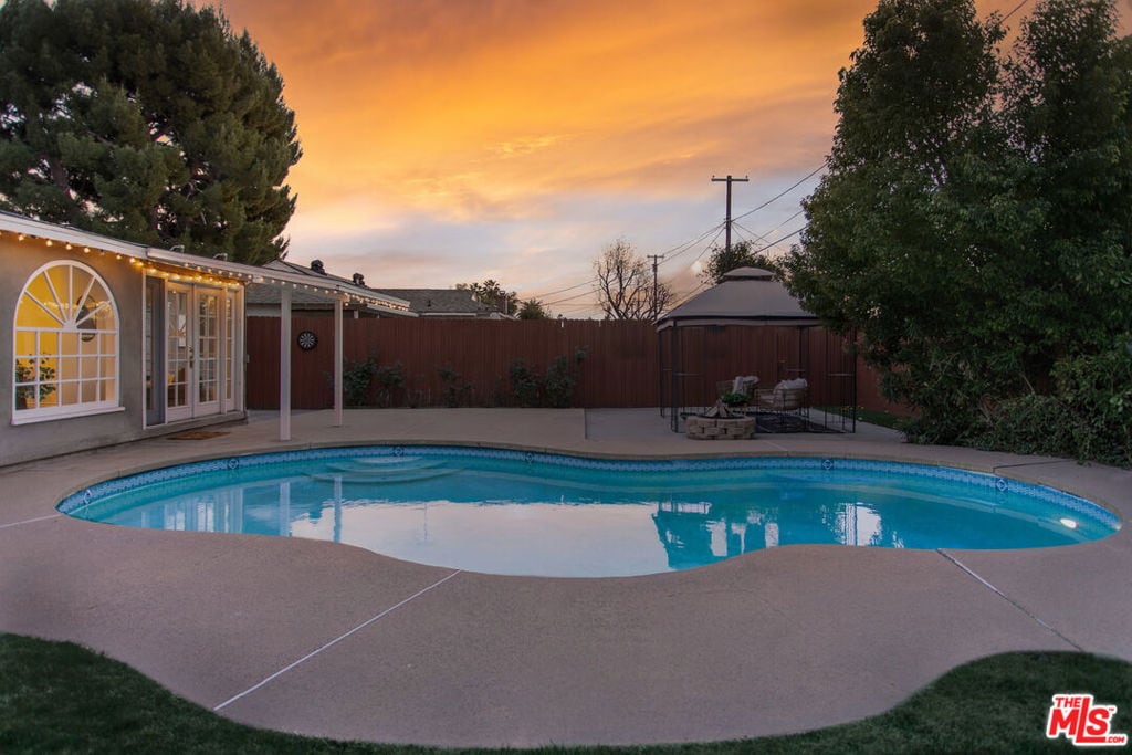 pool at dusk with a patio area and a gazebo