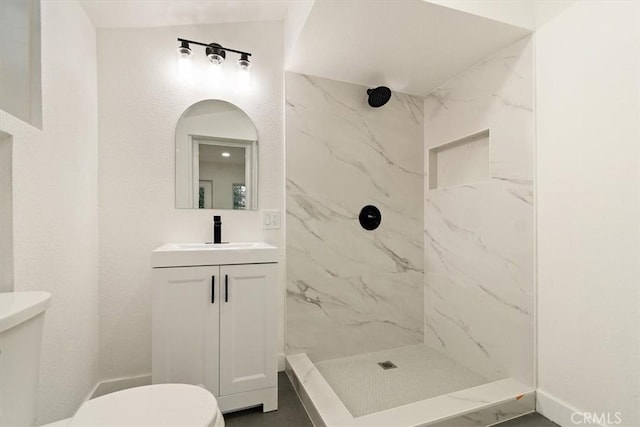 bathroom with toilet, vanity, and a tile shower