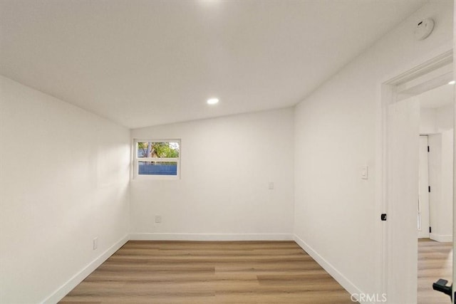 spare room with wood-type flooring and lofted ceiling