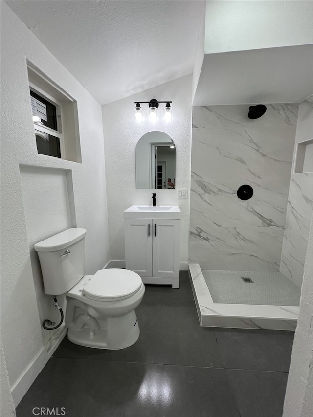 bathroom with a textured ceiling, tiled shower, vanity, and toilet