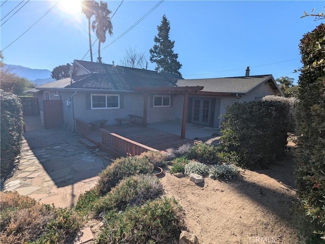 rear view of property featuring a patio, french doors, fence, and stucco siding