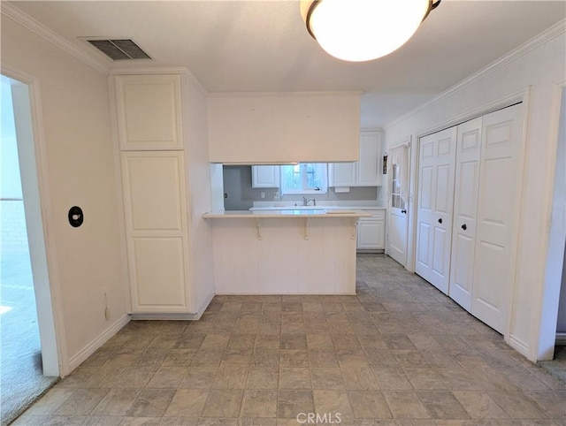 kitchen featuring a kitchen breakfast bar, white cabinetry, crown molding, and kitchen peninsula