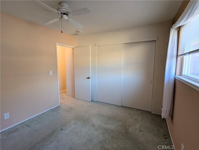 unfurnished bedroom featuring a closet, light colored carpet, and ceiling fan