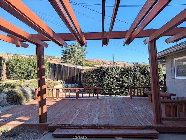 deck with a mountain view, a pergola, and fence