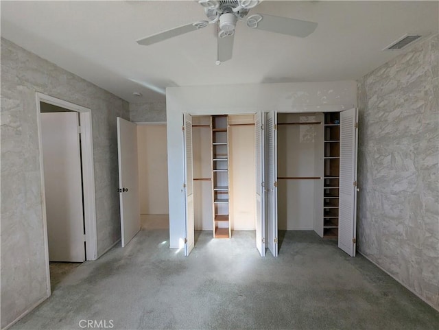 unfurnished bedroom with ceiling fan and multiple closets