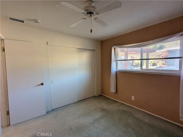 unfurnished bedroom featuring ceiling fan, a closet, and light carpet