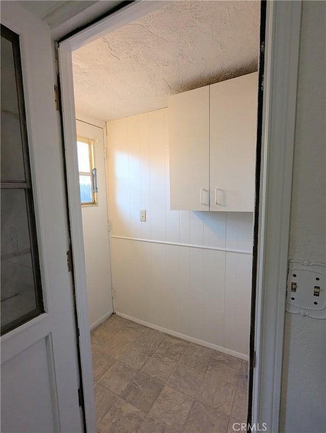 laundry area with baseboards and a textured ceiling