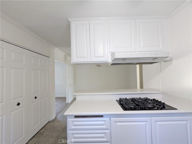 kitchen featuring under cabinet range hood, white cabinetry, light countertops, and black gas stovetop