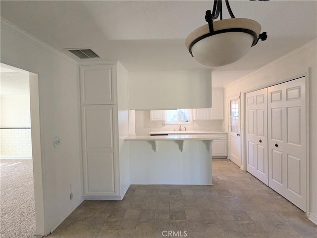 kitchen featuring visible vents, a breakfast bar, white cabinetry, a peninsula, and light countertops