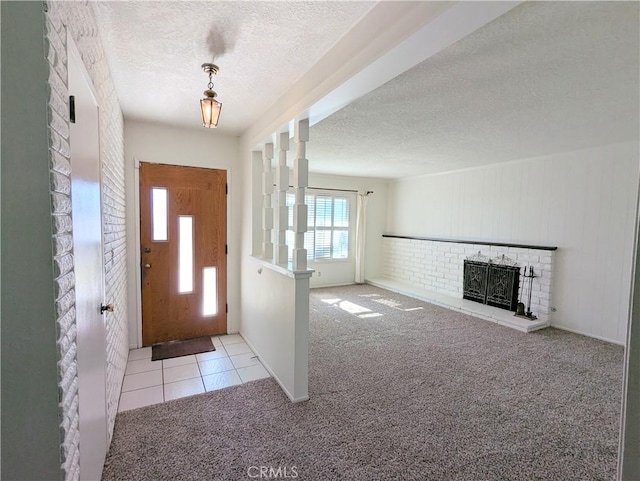 foyer entrance featuring a brick fireplace, carpet flooring, and a textured ceiling