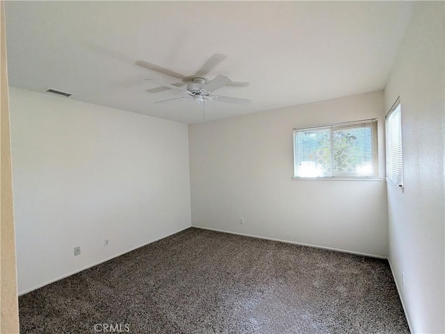 carpeted spare room with visible vents and a ceiling fan