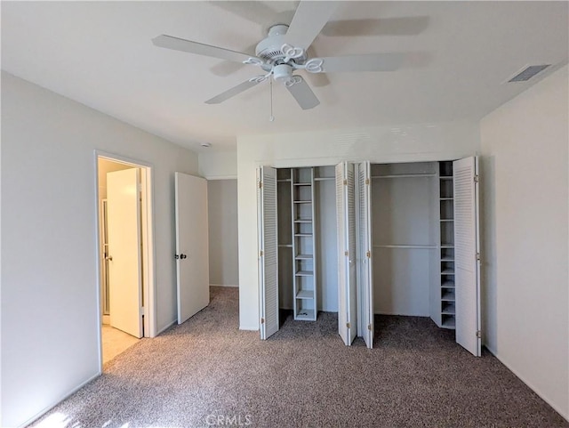 unfurnished bedroom with visible vents, carpet flooring, multiple closets, and ceiling fan