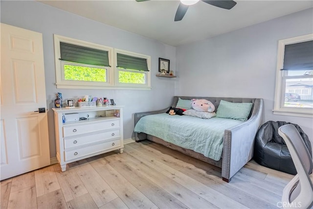 bedroom featuring ceiling fan, light hardwood / wood-style flooring, and multiple windows