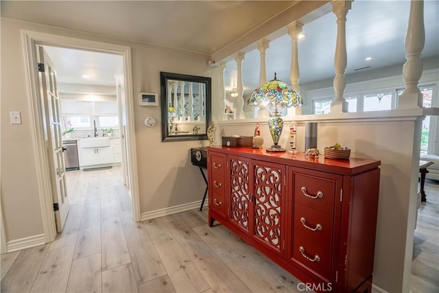 corridor with sink, light hardwood / wood-style flooring, and a wealth of natural light