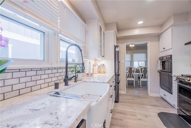 kitchen featuring white cabinets, a healthy amount of sunlight, and light stone countertops