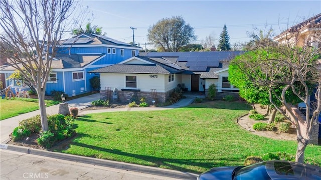 view of front of home with solar panels and a front lawn