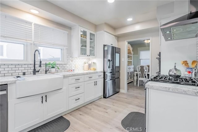 kitchen featuring light stone counters, light hardwood / wood-style flooring, stainless steel appliances, white cabinets, and sink