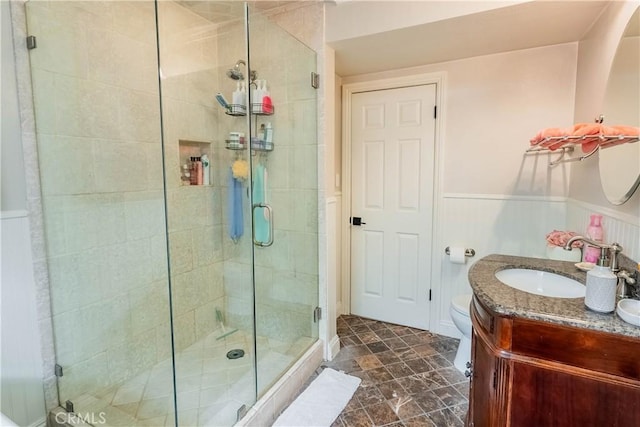 bathroom with toilet, a shower with door, and vanity