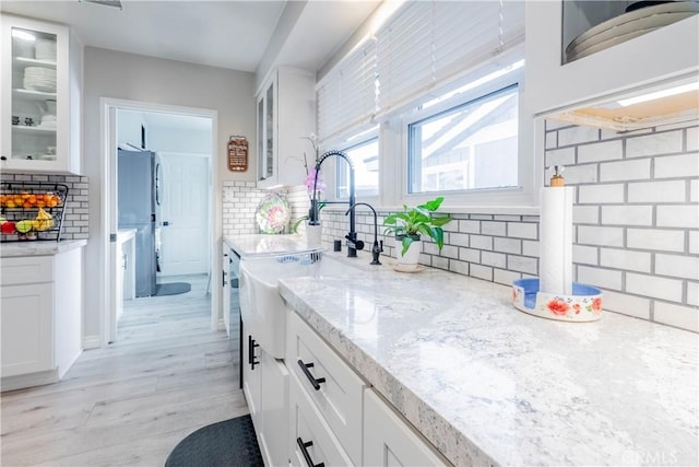 kitchen with white cabinetry, light stone counters, and decorative backsplash