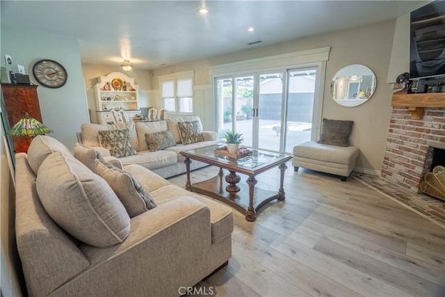 living room featuring a brick fireplace and light hardwood / wood-style flooring