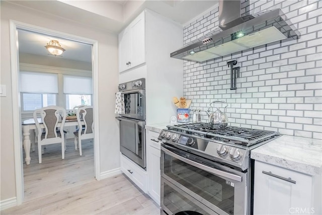 kitchen with appliances with stainless steel finishes, white cabinets, decorative backsplash, and wall chimney exhaust hood