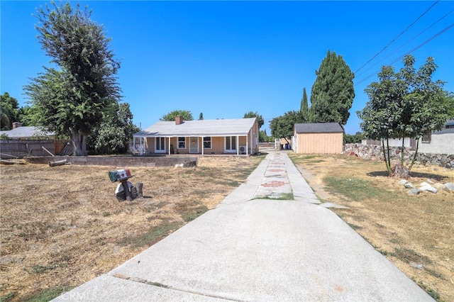 single story home with a porch, a front lawn, and a shed