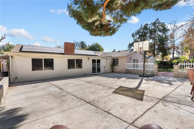 rear view of property featuring solar panels and a patio