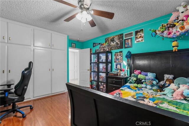 bedroom with ceiling fan, light hardwood / wood-style floors, a closet, and a textured ceiling