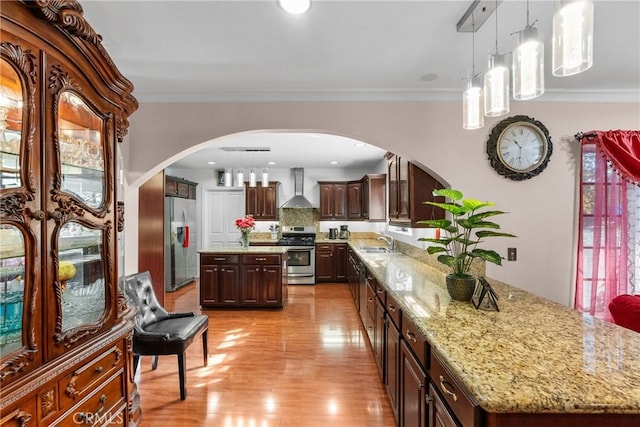 kitchen featuring sink, wall chimney range hood, a center island, and appliances with stainless steel finishes