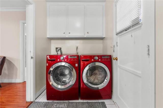 washroom with ornamental molding, cabinets, washing machine and dryer, and light tile patterned flooring