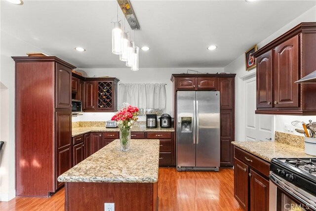 kitchen featuring stainless steel appliances, light hardwood / wood-style flooring, a kitchen island, and hanging light fixtures