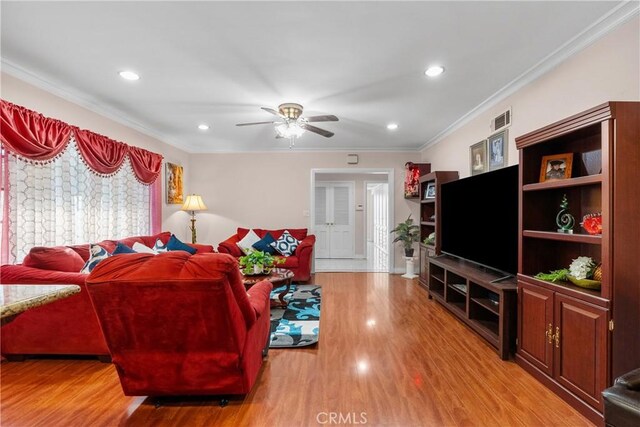 living room with ceiling fan, light wood-type flooring, and ornamental molding