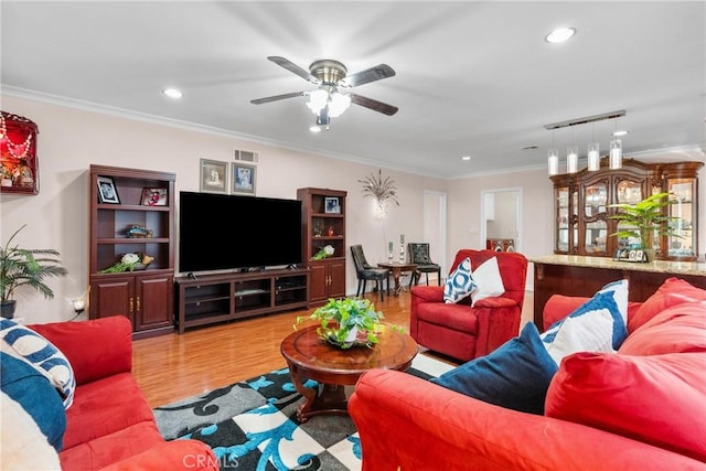 living room featuring rail lighting, ceiling fan, ornamental molding, and light hardwood / wood-style floors