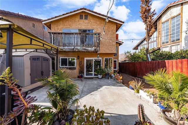 back of house with a balcony, a patio, and a shed