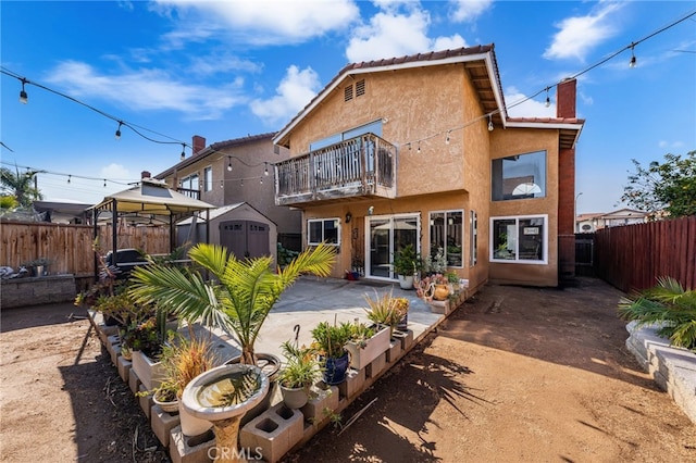 back of property featuring a gazebo, a balcony, a shed, and a patio area