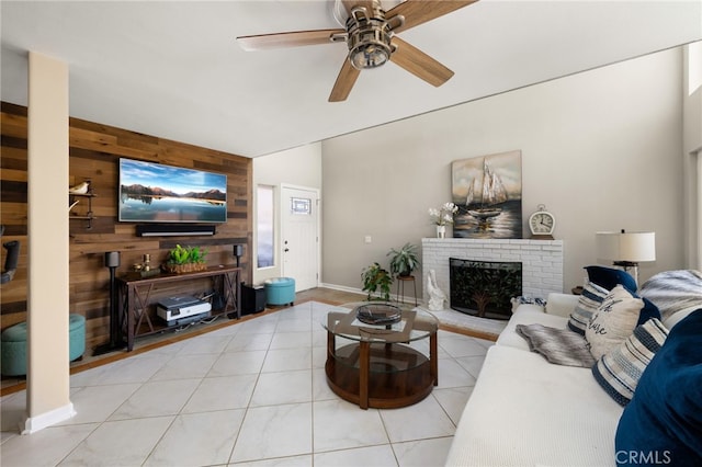 tiled living room featuring a brick fireplace, wooden walls, and ceiling fan