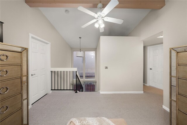 unfurnished room with a ceiling fan, light colored carpet, vaulted ceiling with beams, and baseboards