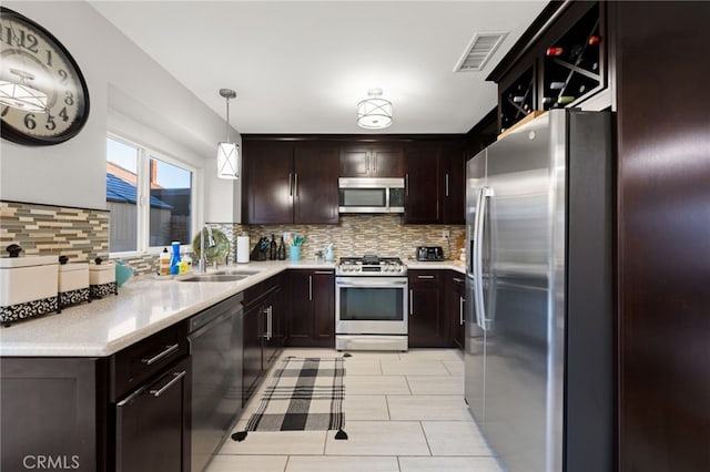 kitchen featuring decorative light fixtures, light countertops, visible vents, appliances with stainless steel finishes, and a sink