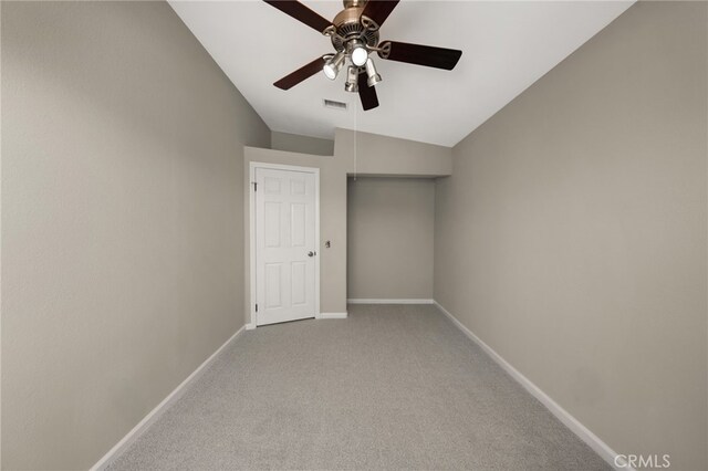 empty room featuring light colored carpet, visible vents, vaulted ceiling, ceiling fan, and baseboards